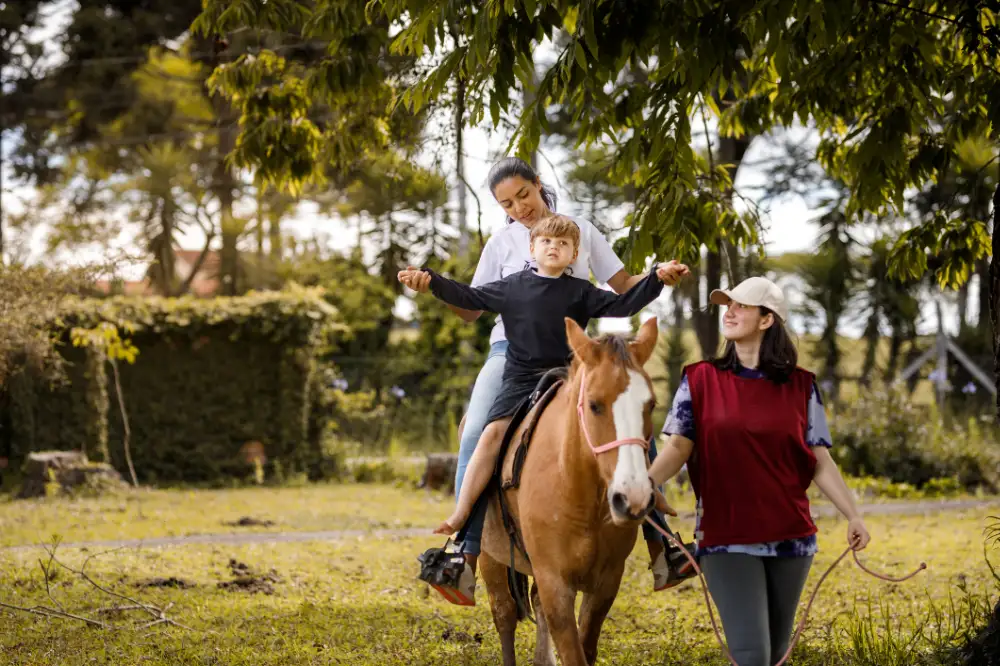 éducatrices spécialisées faisant découvrir l'équitation à un enfant porteur de handicap psychique